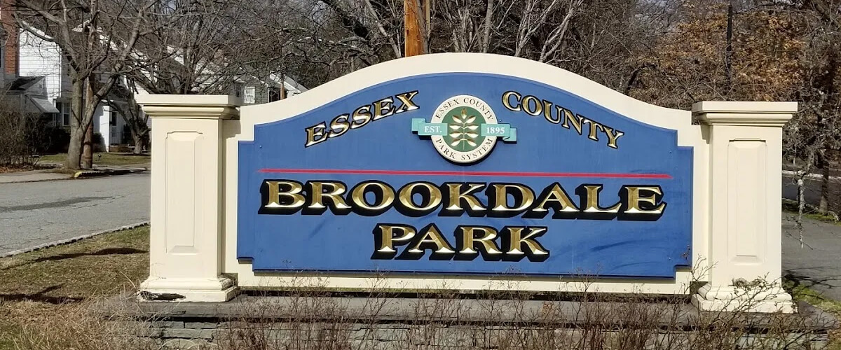 Sign for Brookdale Park in Essex County, with blue panel and white columns on a grassy area.